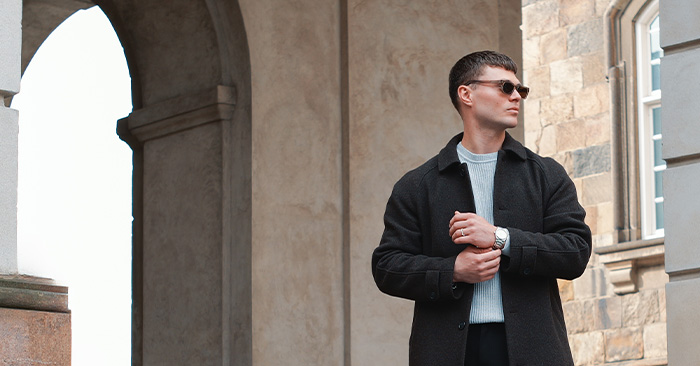 Sale banner male model in a black coat with a classic steel wristwatch with a beige dial